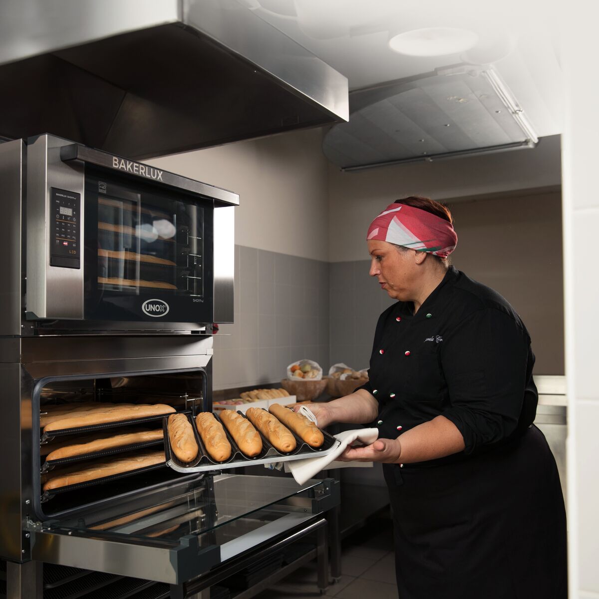 Panadera profesional cargando baguettes en horno UNOX